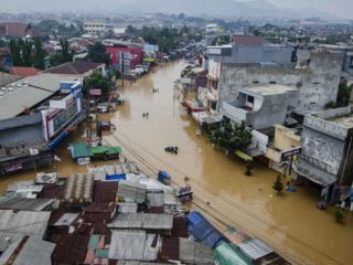 Warga menggunakan perahu melewati genangan banjir di Dayeuhkolot, Kabupaten Bandung, Jawa Barat, Jumat (12/1/2024). (Foto: ANTARA FOTO/NOVRIAN ARBI)