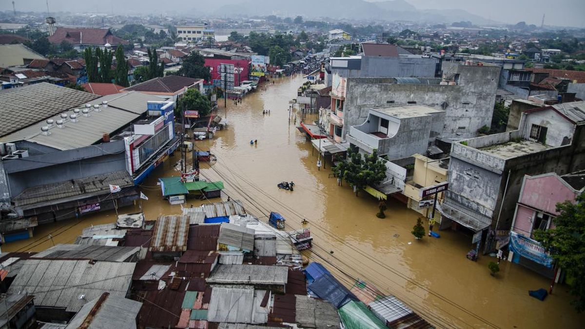 Warga menggunakan perahu melewati genangan banjir di Dayeuhkolot, Kabupaten Bandung, Jawa Barat, Jumat (12/1/2024). (Foto: ANTARA FOTO/NOVRIAN ARBI)